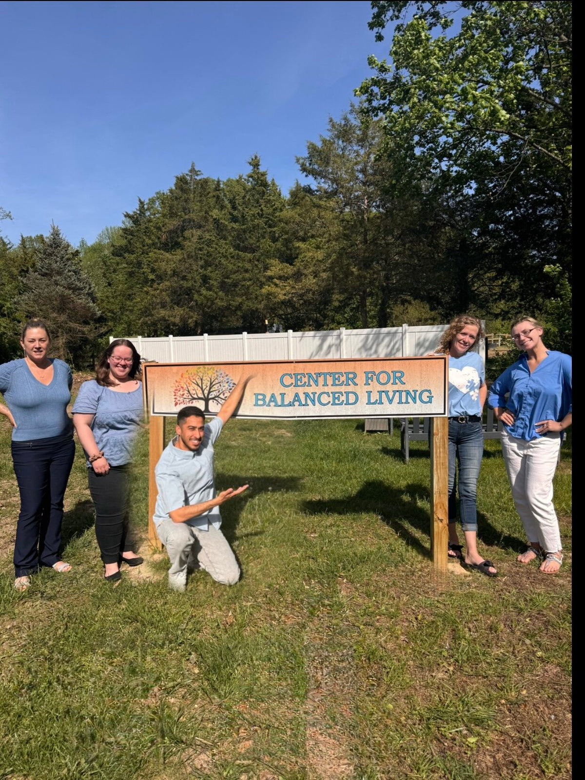 The Center for Balanced Living team in blue beside the practice sign for Autism Awareness Day, 2024