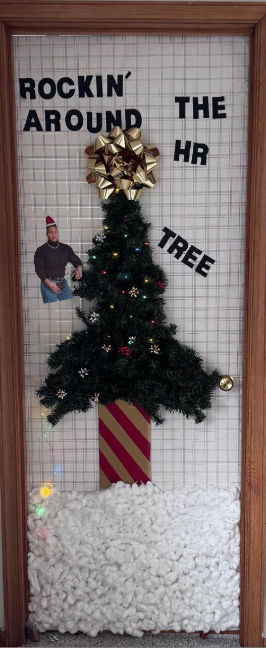 Office door decorated as Rockin' Around the HR Tree, with a tree, a gold bow and paper snow